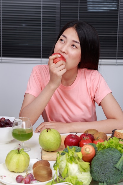 jonge vrouw die appel in keuken eet