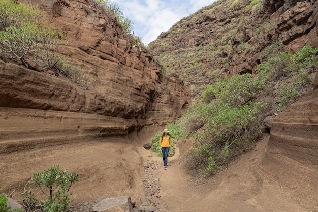 Jonge vrouw die Barranco de las Vacas, Gran Canaria, Canarische Eilanden Spanje onderzoeken. Geologie, vulkanisch landschap en vakantie concept.