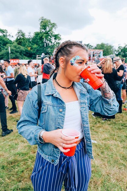 Jonge vrouw die bij een boom tegen de lucht staat