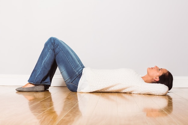 Jonge vrouw die bij vloer het denken ligt