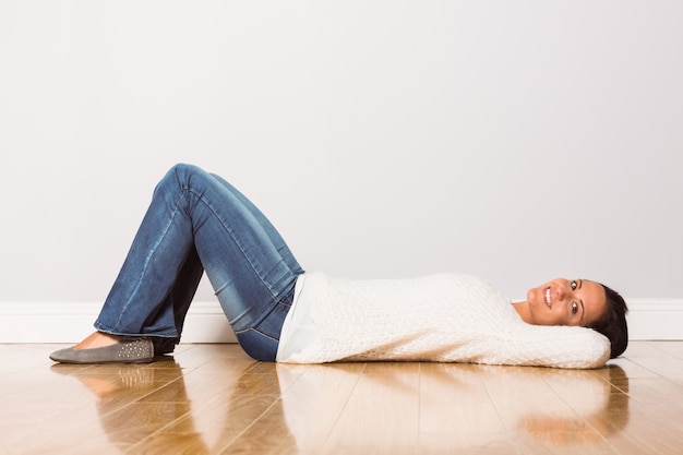 Foto jonge vrouw die bij vloer het glimlachen ligt