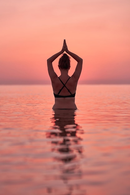 Jonge vrouw die bij zonsopgang in de zee zwemt