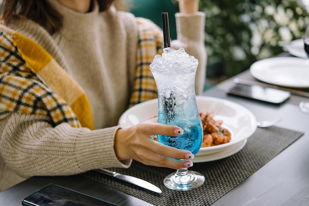 Jonge vrouw die blauwe lagunecocktail drinkt