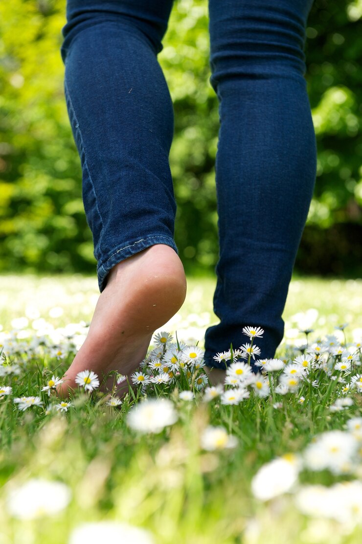 Jonge vrouw die blootvoets op groen gras in het park loopt