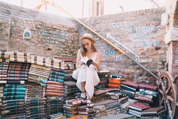 Jonge vrouw die boek in oude tweedehands boekhandel libreria acqua alta in venetië italië kiest