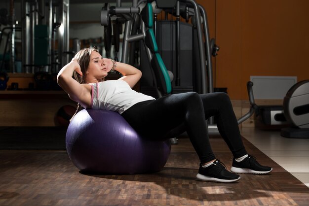 Jonge vrouw die buikspieren traint in de fitnessclub