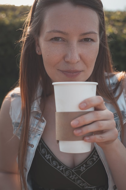 Jonge vrouw die buiten koffie drinkt