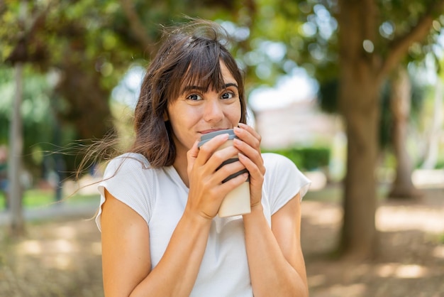 Jonge vrouw die buitenshuis een afhaalkoffie houdt