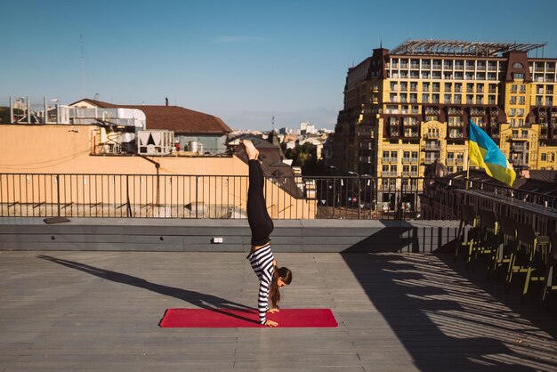 Jonge vrouw die buitenshuis traint en yoga handstandoefening doet