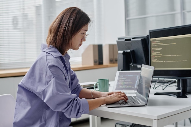 Jonge vrouw die codes op laptop typt