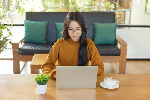 Foto jonge vrouw die computer gebruikt in een café