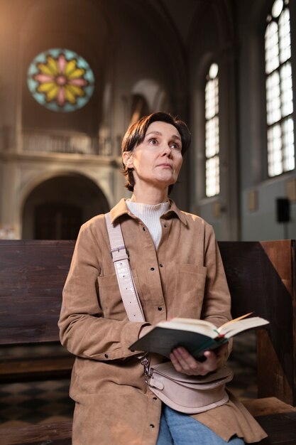 Foto jonge vrouw die de bijbel in de kerk leest