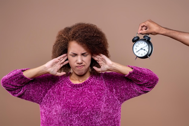 Jonge vrouw die de oren sluit van het klokgeluid