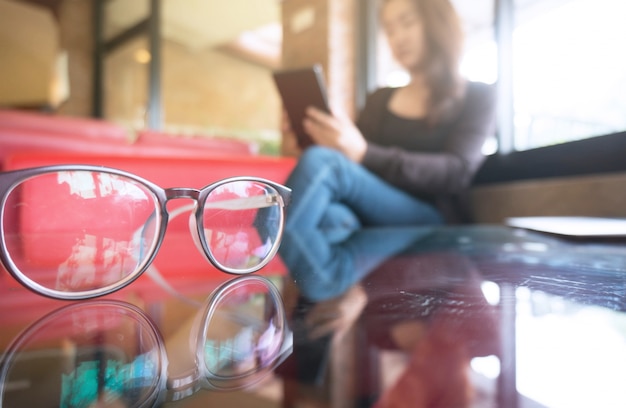 Jonge vrouw die de tablet houdt en thuis zitten. geselecteerde focus op brillen.