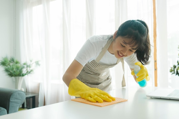 Jonge vrouw die de tafel schoonmaakt die thuis handschoenen draagt