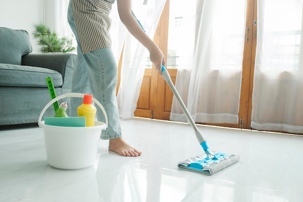 Jonge vrouw die de vloer schoonmaakt met dweil thuis