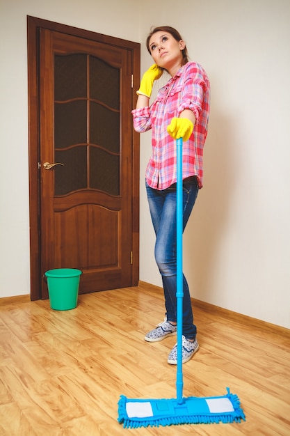 Foto jonge vrouw die de vloer schoonmaakt