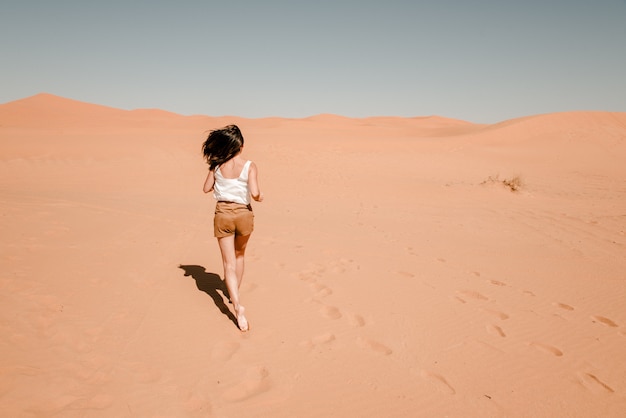 Jonge vrouw die de zandduinen doorneemt in de woestijn