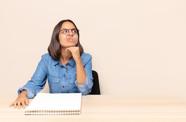 Jonge vrouw die denkt, zich twijfelachtig en verward voelt, met verschillende opties, zich afvraagt welke beslissing ze moet nemen