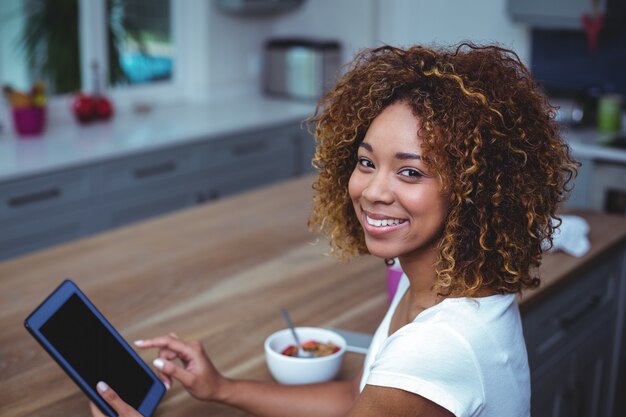 Jonge vrouw die digitale tablet gebruikt terwijl het zitten door lijst