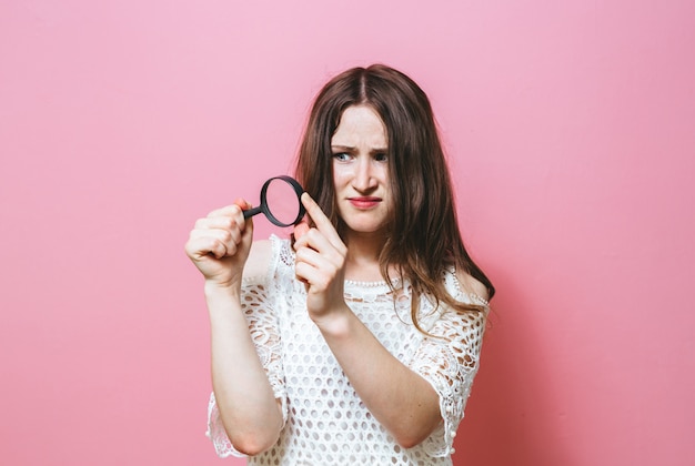 Jonge vrouw die door een vergrootglas kijkt