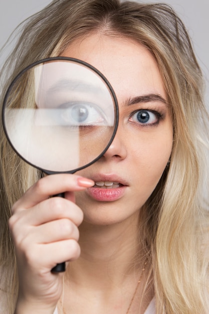 Jonge vrouw die door een vergrootglas kijkt