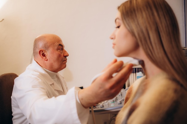 Jonge vrouw die door haar arts in een moderne kliniek een echografie van haar nek krijgt. Schildklierhormonen worden gecontroleerd. Hyperthyroidisme, hypothyroidisme.