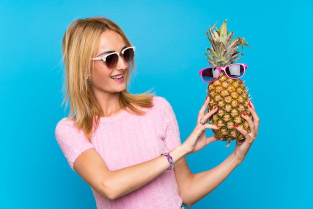 Jonge vrouw die een ananas met zonnebril houdt