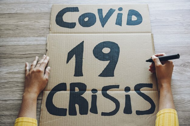 Jonge vrouw die een banner voorbereidt voor Covid 19 economische crisisprotest