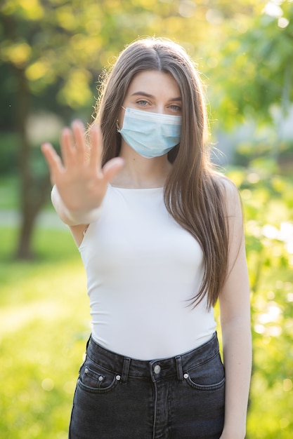 Jonge vrouw die een beschermend masker in het park draagt