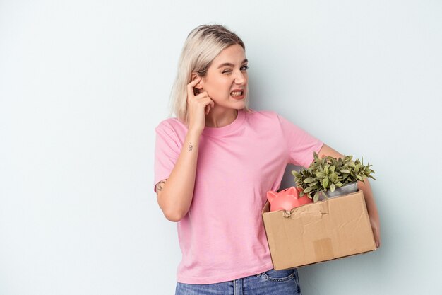 Jonge vrouw die een beweging maakt over geïsoleerde achtergrond die oren bedekt met handen.