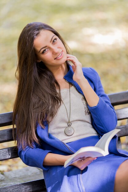 Jonge vrouw die een boek in het park leest