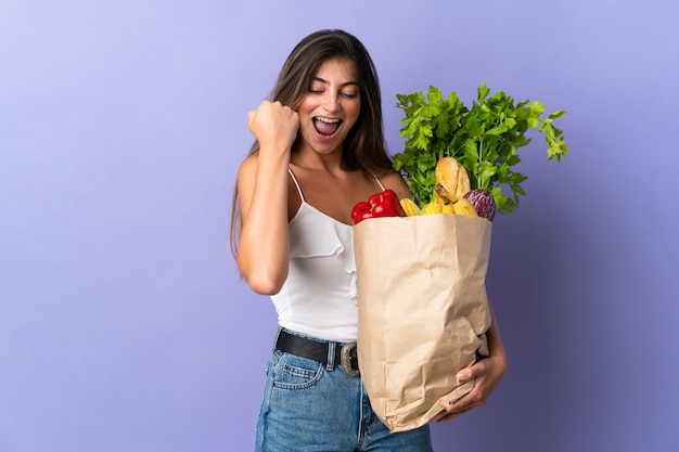 Jonge vrouw die een boodschappentas houdt die een overwinning viert