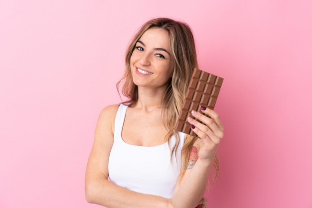 Jonge vrouw die een chocolade over geïsoleerde muur houdt