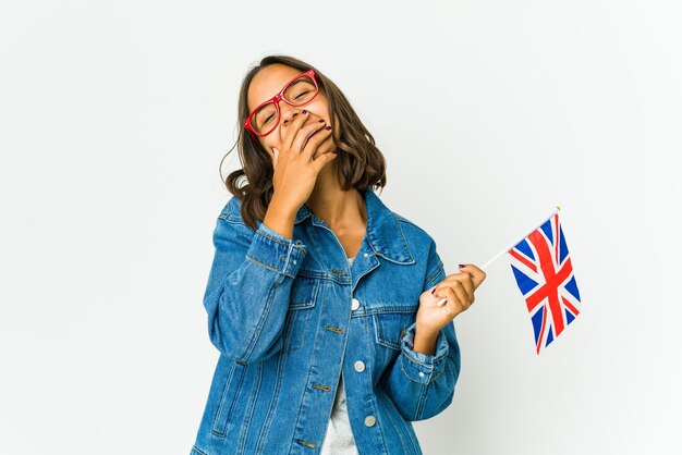 Jonge vrouw die een engelse vlag houdt die op witte muur wordt geïsoleerd die gelukkige, zorgeloze, natuurlijke emotie lacht