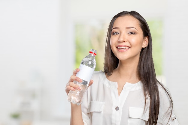Jonge vrouw die een fles water toont