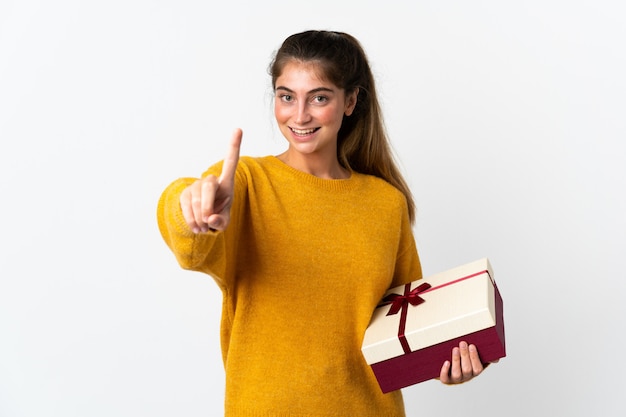 Jonge vrouw die een gift houdt die op wit wordt geïsoleerd en een vinger opheft