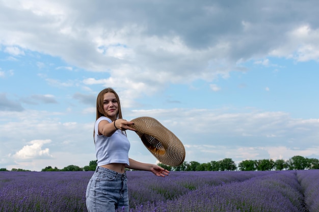 Foto jonge vrouw die een hoed gooit in een lavendelveld.