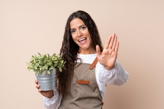 Jonge vrouw die een installatie het groeten met hand met gelukkige uitdrukking houdt