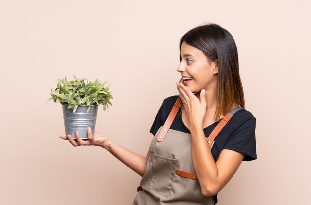 Jonge vrouw die een installatie met verrassing en geschokte gelaatsuitdrukking houdt