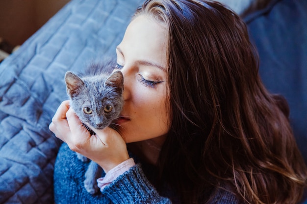 Jonge vrouw die een katje met tedere liefde kust.