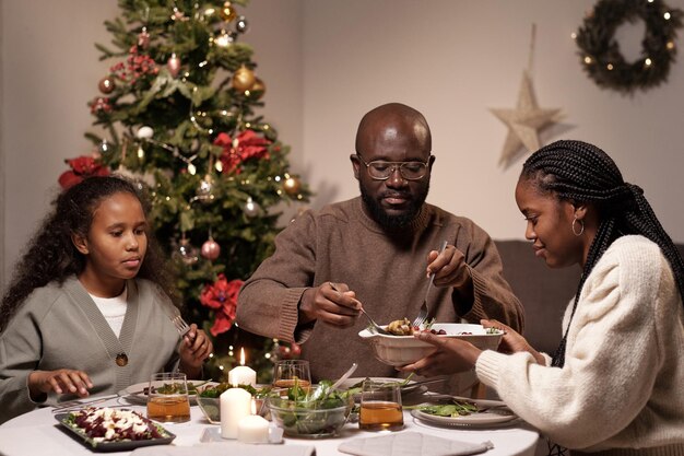 Jonge vrouw die een kom met eten vasthoudt terwijl haar man een stuk vlees neemt