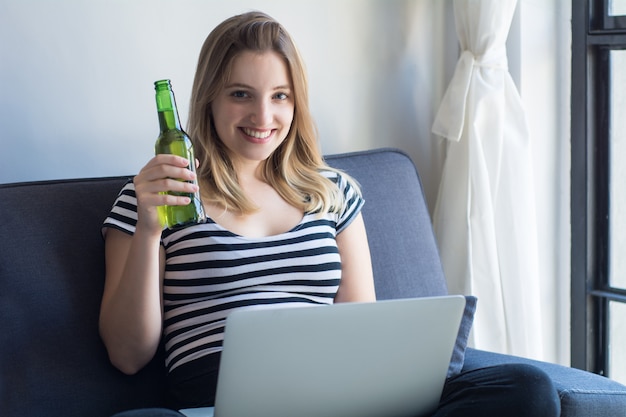 Jonge vrouw die een laptop computer thuis met behulp van