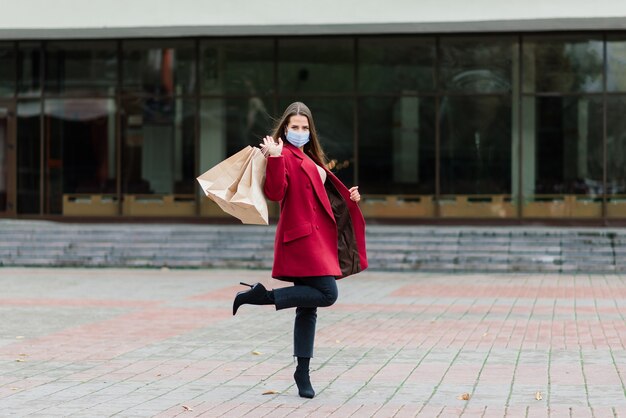 Jonge vrouw die een masker draagt om het virus te voorkomen met boodschappentassen op een smal straatje in europa.