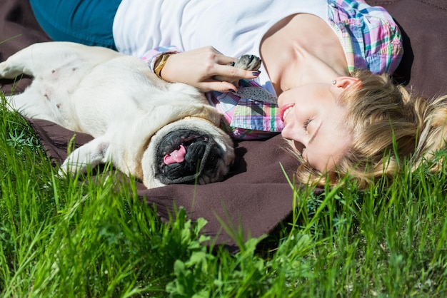 Foto jonge vrouw die een mopshond loopt in een groen park