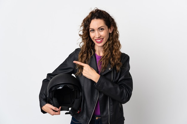 Jonge vrouw die een motorhelm houdt die naar de kant wijst om een product te presenteren