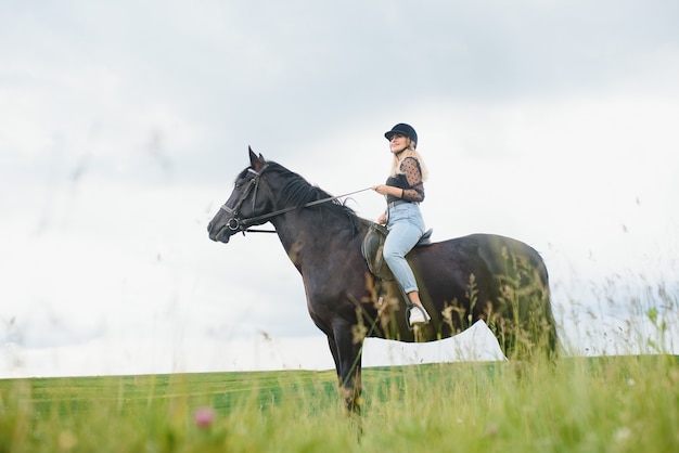 Jonge vrouw die een paard berijdt op het groene veld