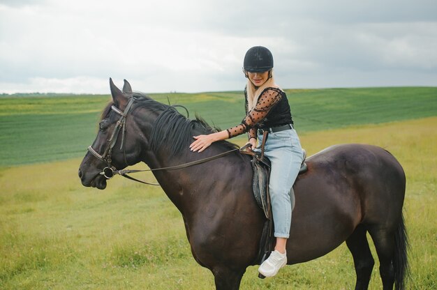 Jonge vrouw die een paard berijdt op het groene veld