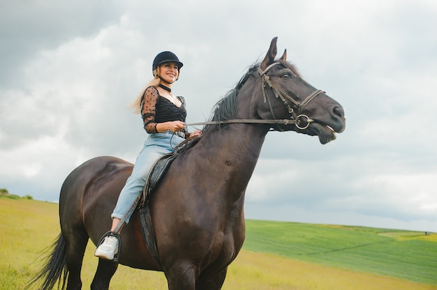 Jonge vrouw die een paard berijdt op het groene veld