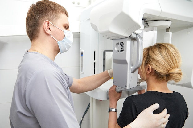 Jonge vrouw die een panoramische opname maakt van de kaak die haar gezicht vasthoudt aan de xray-machine